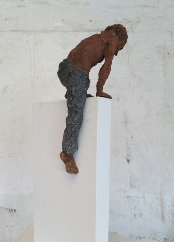 tornem-hi|teresa riba|escultura de bronze d'un noi que puja per la paret